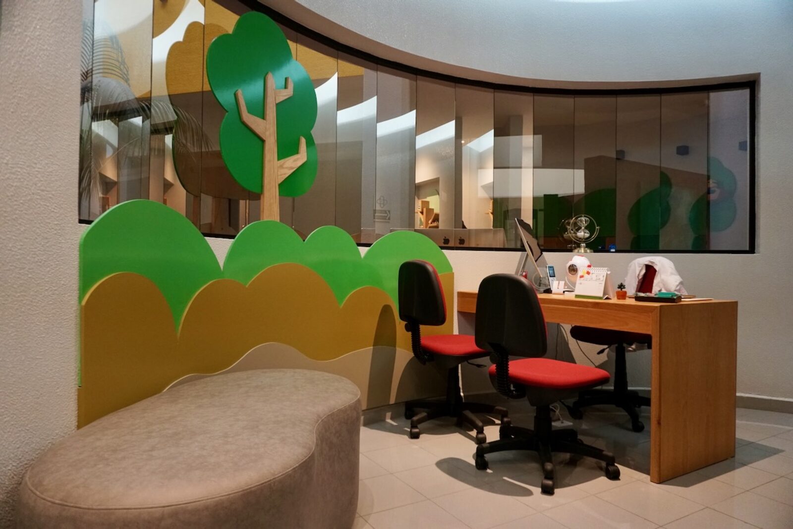 Recepción del consultorio de oftalmología pediátrica con mural de bosque y mobiliario infantil