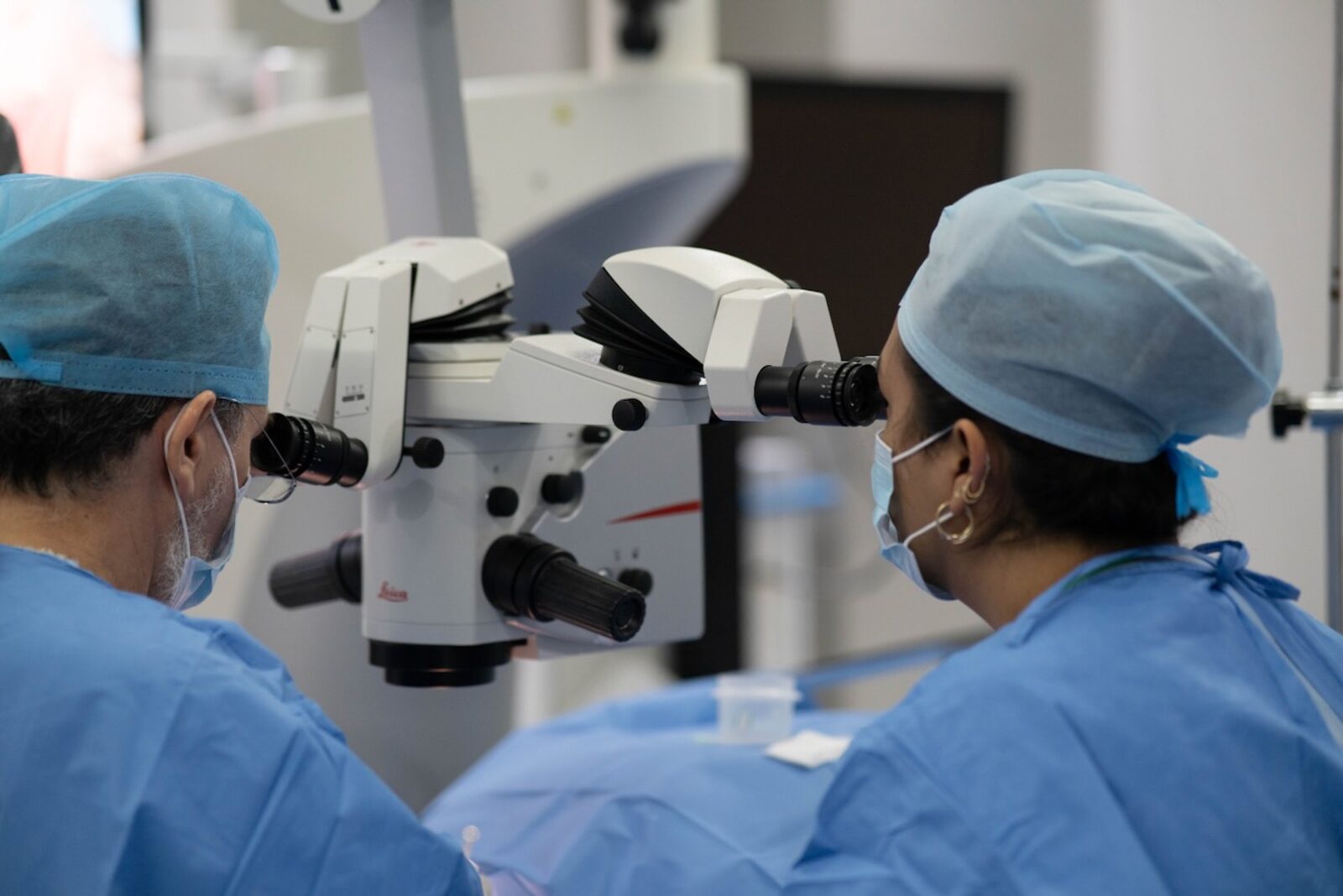 Cirujanos operando con microscopio quirúrgico de alta precisión